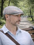Man in gray plaid linen newsboy cap three quarter view park setting