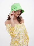 Woman wearing bright green cotton bucket cloche hat with yellow printed dress