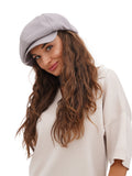 Woman in cream oversized sweater wearing grey cotton newsboy cap close-up portrait