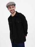 Full body shot man in grey herringbone newsboy cap with black shirt and dark blue jeans