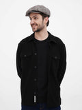 Torso front view man in grey herringbone 8-panel newsboy cap smiling with black shirt