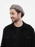 Grey herringbone 8-panel newsboy cap front view smiling with black shirt