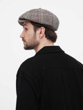 Casual front view man wearing grey herringbone baker boy hat smiling with black shirt