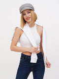 Woman in grey linen Breton cap looking over shoulder, white top and jeans
