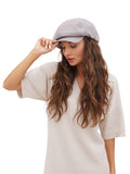Woman adjusting brim of grey cotton paperboy hat white background
