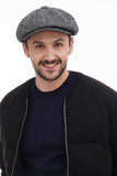 Torso side view man in grey tweed 8-panel newsboy cap with black bomber jacket