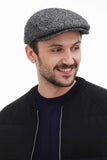 Full body shot man in graphite grey tweed flat cap with black bomber jacket and jeans