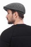 Three quarter view man in grey tweed flat cap with black bomber jacket casual smile
