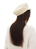 Woman touching brim of ivory cotton Breton sailor cap, leopard print top