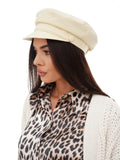 Woman standing in ivory cotton Breton sailor cap and white cardigan