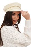 Woman wearing ivory cotton Greek fisherman cap with white knit cardigan, close-up