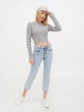 Woman in ivory linen baker boy cap, grey top and jeans full length