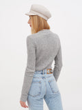 Side view of woman wearing ivory linen Breton cap, touching brim