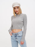 Woman wearing ivory linen Breton cap with grey ribbed top, hand on hip