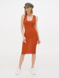 Woman in rust dress and khaki linen newsboy cap standing full length