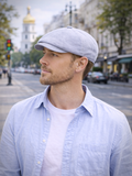 Man in light blue linen baker boy hat three quarter view urban