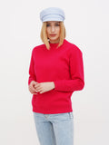 Front view of woman wearing light blue linen Breton cap and red sweater