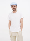Man in light blue linen newsboy cap full body beige pants
