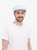 Man wearing light blue linen newsboy cap front view smiling