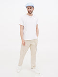 Man wearing light blue linen cap full body white t-shirt beige pants