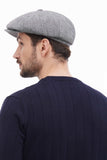 Smiling man wearing light grey tweed baker boy hat close-up portrait with navy sweater