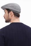 Torso side view man wearing light grey tweed flat cap with navy sweater