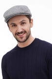 Close-up front view man wearing light grey tweed flat cap showing texture with navy sweater