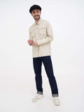 Man wearing black slouchy newsboy cap with beige jacket and dark jeans full body view