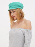 Side profile of woman wearing mint green linen Breton cap and grey dress