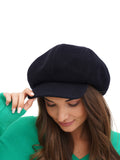 Woman adjusting brim of navy blue wool baker boy cap portrait view