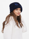 Woman wearing navy blue wool cloche hat with stone flower accent, cream sweater