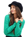 Woman in emerald green sweater wearing navy blue wool newsboy cap portrait