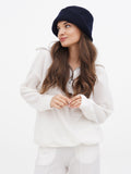 Side profile of woman in navy cloche hat with cream cardigan