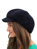 Three-quarter face view woman in navy wool newsboy cap with long dark hair