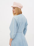 Woman wearing peach linen Breton cap looking sideways in light blue dress