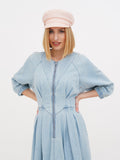 Woman wearing peach linen Breton cap with light blue dress, hands on hips