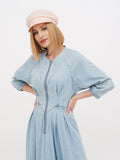 Side profile of woman in peach linen newsboy cap with light blue dress