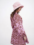 Woman in pink bucket hat and floral dress, full outfit standing