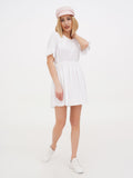 Woman in pink linen baker boy cap and white dress, full length side angle