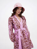 Woman in pink sun hat and printed dress, walking outdoors