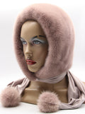 Three-quarter view powder pink mink hood showing smooth dyed pile and pale fabric scarf with pompon