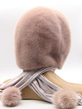 Detail view powder pink mink pompon at end of fabric scarf showing compact mink pompon construction