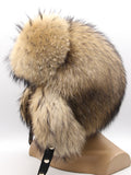 Left profile of raccoon fur hat with ear flaps pulled back and tied behind the head