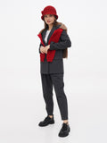 Woman in red cloche hat standing, black pants, camel coat