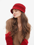 Woman wearing red cloche hat, three-quarter angle, camel sweater