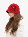 Woman wearing red wool cloche hat with side bow, cream sweater