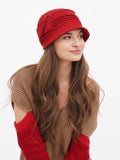 Woman wearing red wool cloche hat with pin-tucked seams, camel sweater
