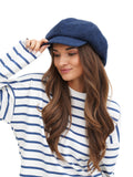 Smiling woman portrait in royal blue wool baker boy cap and white striped top