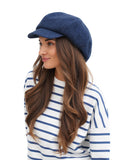 Woman adjusting brim of royal blue wool paperboy cap front view portrait