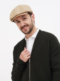 Man wearing sand linen newsboy cap front view black jacket casual